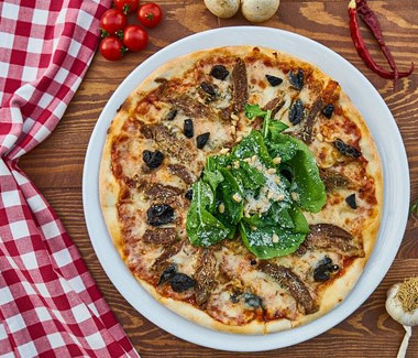 Pizza gourmande aux champignons et roquette de Les Délices de Kenza à Bordeaux sur nappe à carreaux rouges,